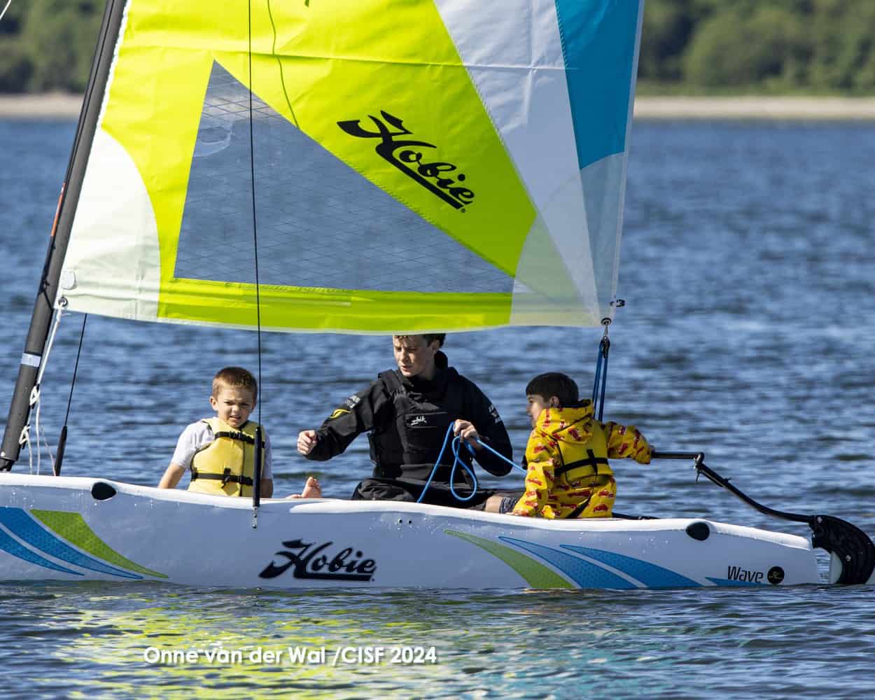 An instructor showing the mainsheet to two kids aboard a Hobie Wave