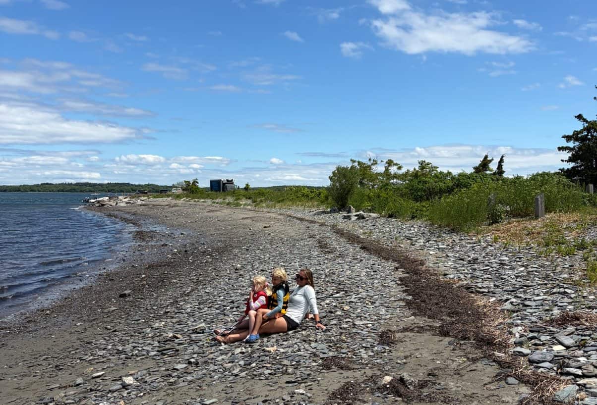 Three campers taking a break together on the rocky beach